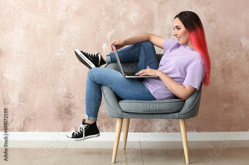 Female programmer using laptop near color wall