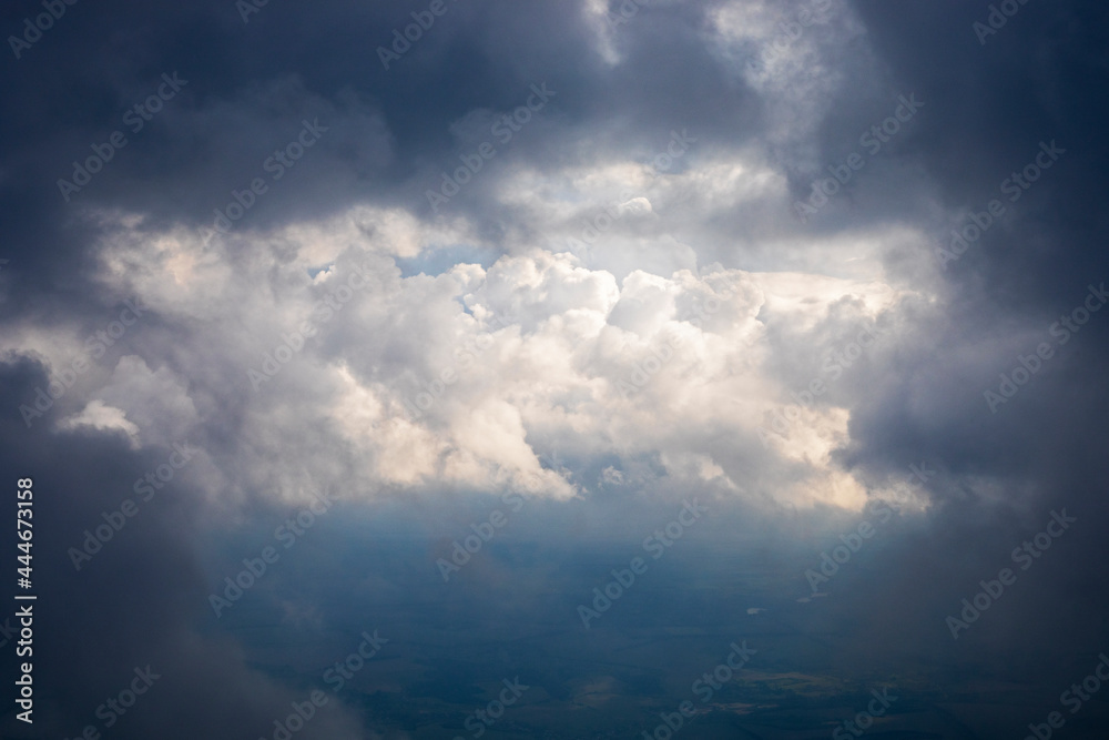 storm clouds through the rays of the sun from the plane window, horizontal.