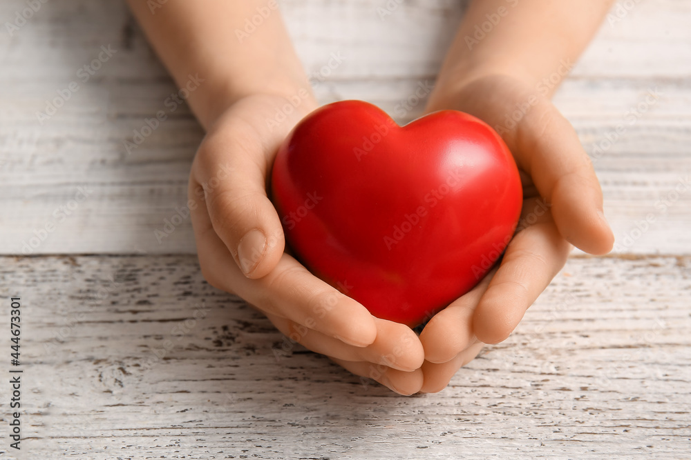 Child's hands with red heart on light wooden background, closeup Child's hands with red heart on light wooden background, closeup