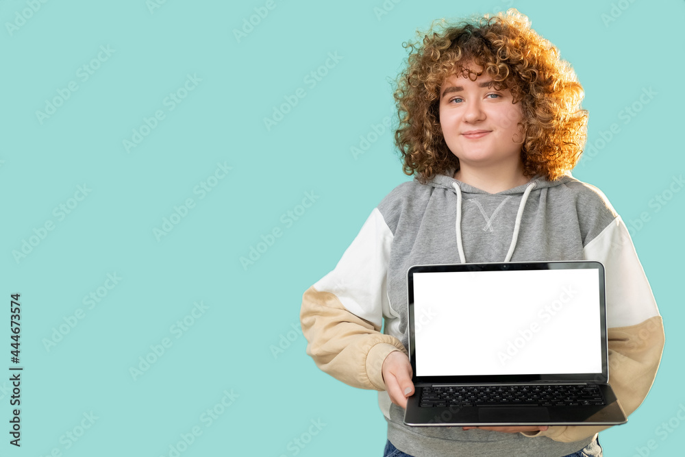 Laptop mockup. Digital technology. Remote job. Body positive. Satisfied overweight woman with curly hair holding blank screen notebook isolated on blue empty space background.