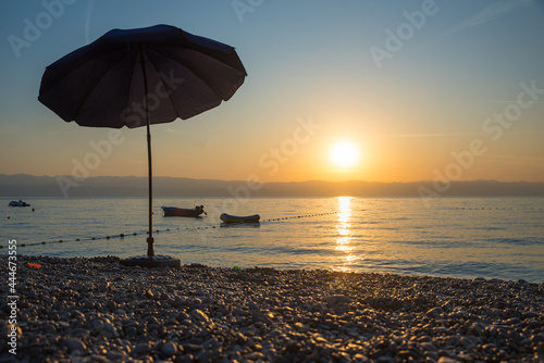 Fototapeta Naklejka Na Ścianę i Meble -  beach scenery with sunshade and boats in the early morning, Moscenicka Draga croatia