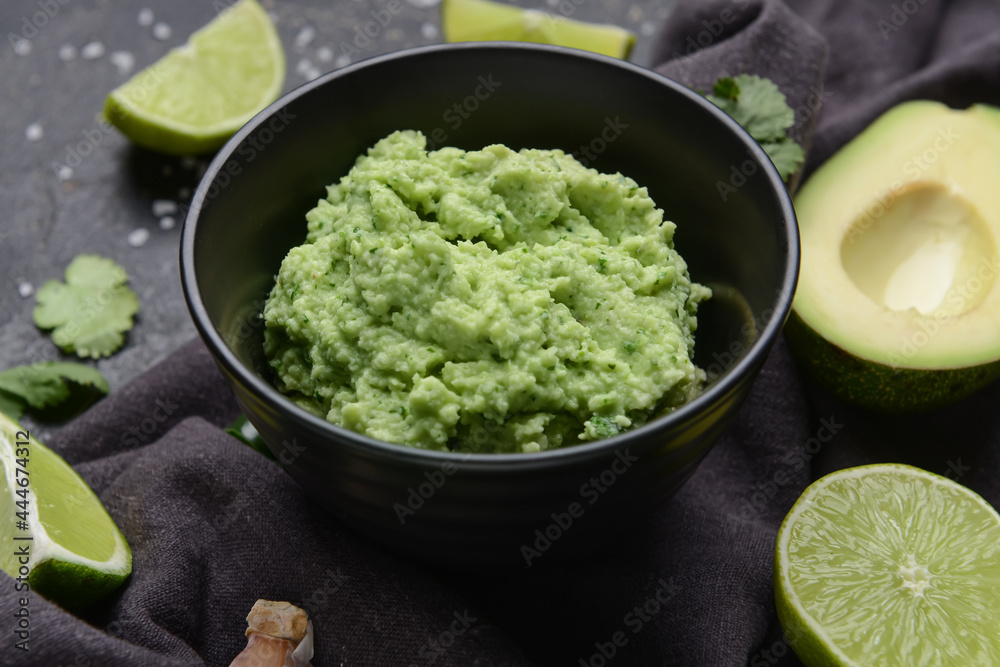 Bowl with tasty guacamole and lime on dark background Bowl with tasty guacamole and lime on dark background