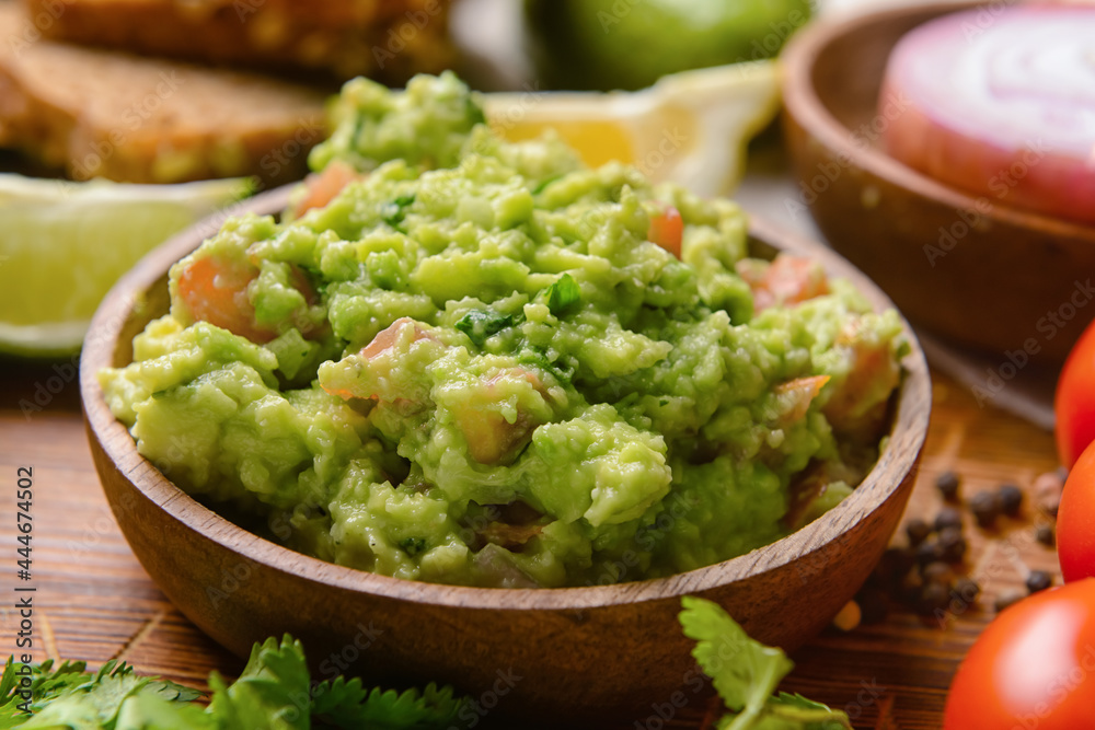 Bowl with tasty guacamole on table, closeup
