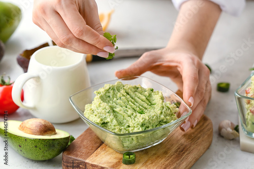 Woman with tasty guacamole on table, closeup