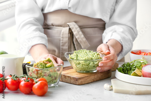 Woman with tasty guacamole on table