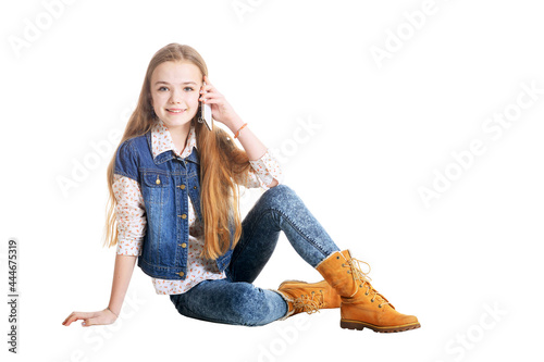 Happy little girl in jeans talking on phone