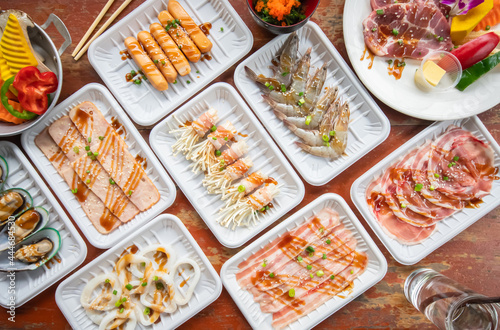 Set ingredients of Freshly sliced pork meat, shrimp, squid, mussels, sliced pork, sausage, ham, and vegetables for Sukiyaki shabu and Japanese food. Top view