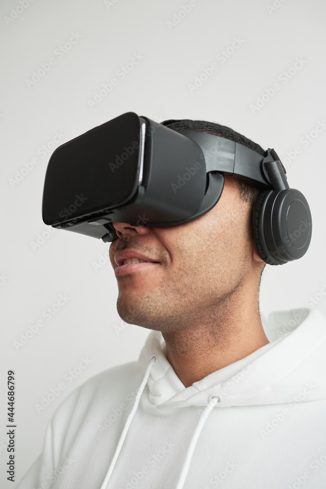 Minimal close up portrait of modern young man wearing VR headset against white background, copy space Minimal close up portrait of modern young man wearing VR headset against white background, copy space