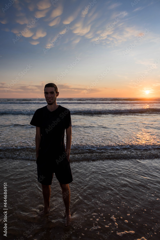 pretty young man on the beach at sunset
