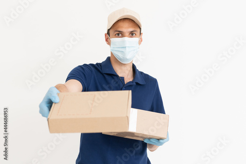 Delivery guy with protective mask and gloves holding box with groceries