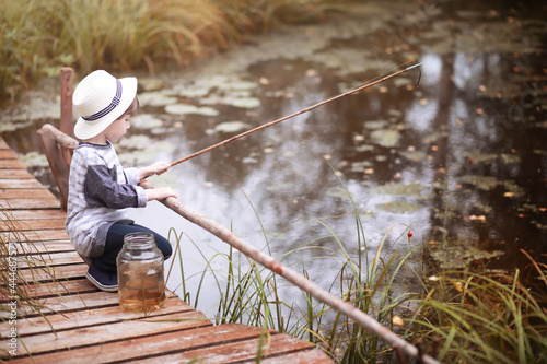 A child is fishing in the autumn morning. Autumn sunset on the pond. A fisherman with a fishing rod on the walkway.