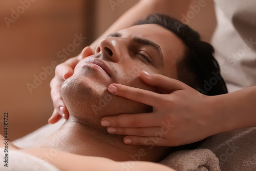 Man receiving facial massage in beauty salon, closeup photo