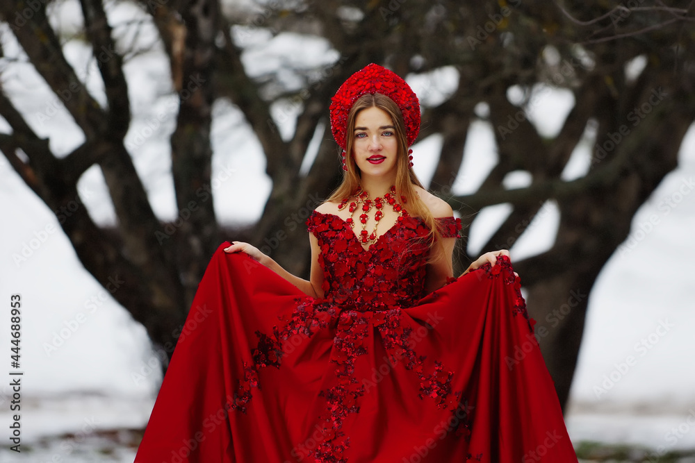 Girl in a red dress in winter on the snow