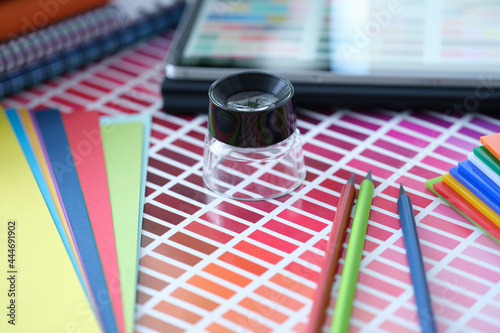 Color palette with pink shades of pencils and colored paper lie on table photo