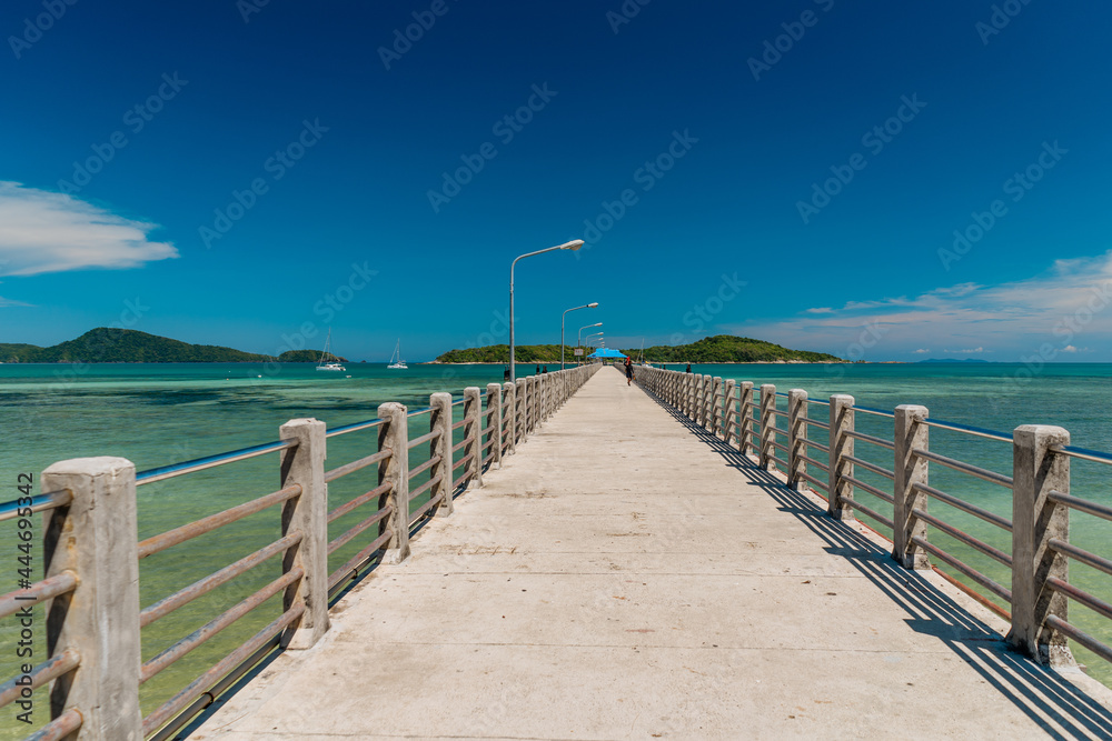 A stone pier leading far into the sea surrounded by crystal clear turquoise sea water, good sunny weather.Summer vacation and nature travel adventure concept..Summer composition.