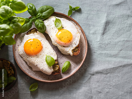 Croque-madame with fried egg , pesto sauce and basil on a linen tablecloth. Traditional French Toasted Sandwich. French cuisine.