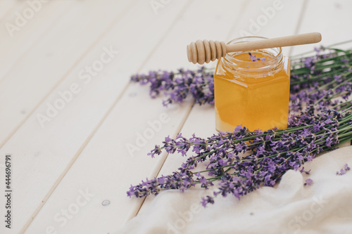 Jar with honey and bunch of lavender on wooden background. Herbal healthy food. photo