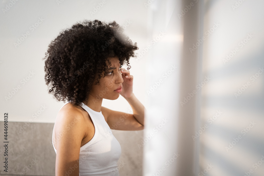 Girl checking her skin in the mirror, skincare, at the bathroom Girl checking her skin in the mirror, skincare, at the bathroom