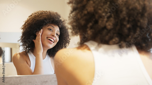 Girl smiling happy checking her skin in the mirror, skincare © Davide Marconcini
