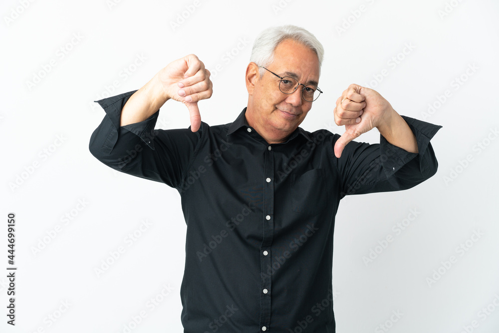 Naklejka premium Middle age Brazilian man isolated on white background showing thumb down with two hands