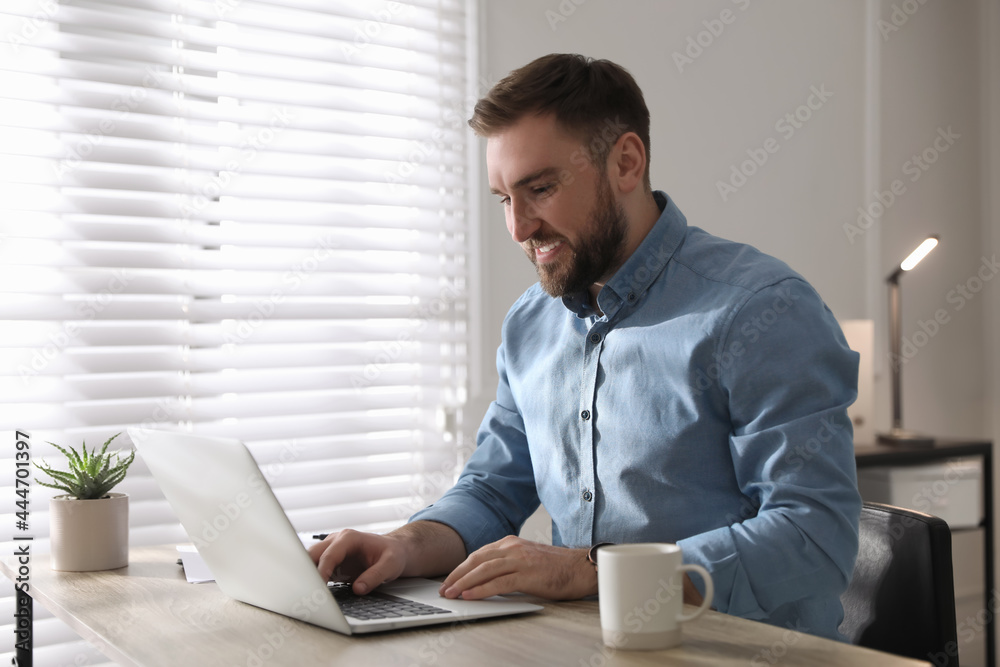 Young man working on laptop at table in office Young man working on laptop at table in office