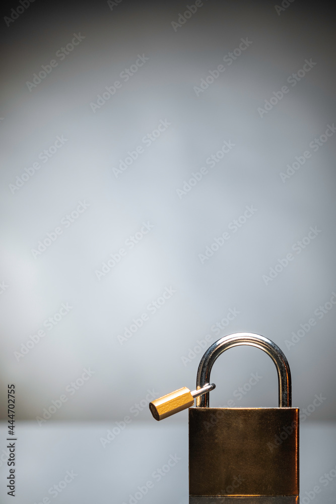 Fototapeta premium Gold iron lock placed on black reflexive glass on black background with tiny lock on it. 