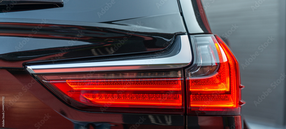 The red headlight of a modern black car. Rear stop light of large suv car. Black premium city crossover The red headlight of a modern black car. Rear stop light of large suv car. Black premium city crossover