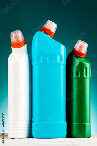 Bottles of detergent and cleaning products on a blue background, space for text.