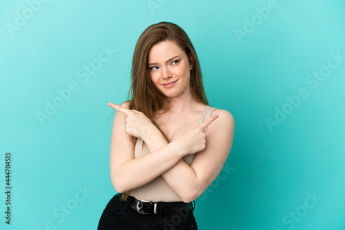 Teenager girl over isolated blue background pointing to the laterals having doubts © luismolinero