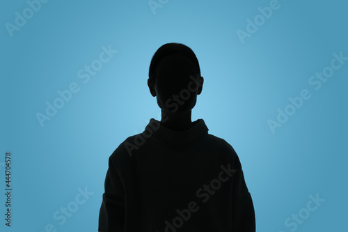 Silhouette of anonymous woman on light blue background