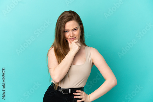 Teenager girl over isolated blue background having doubts © luismolinero