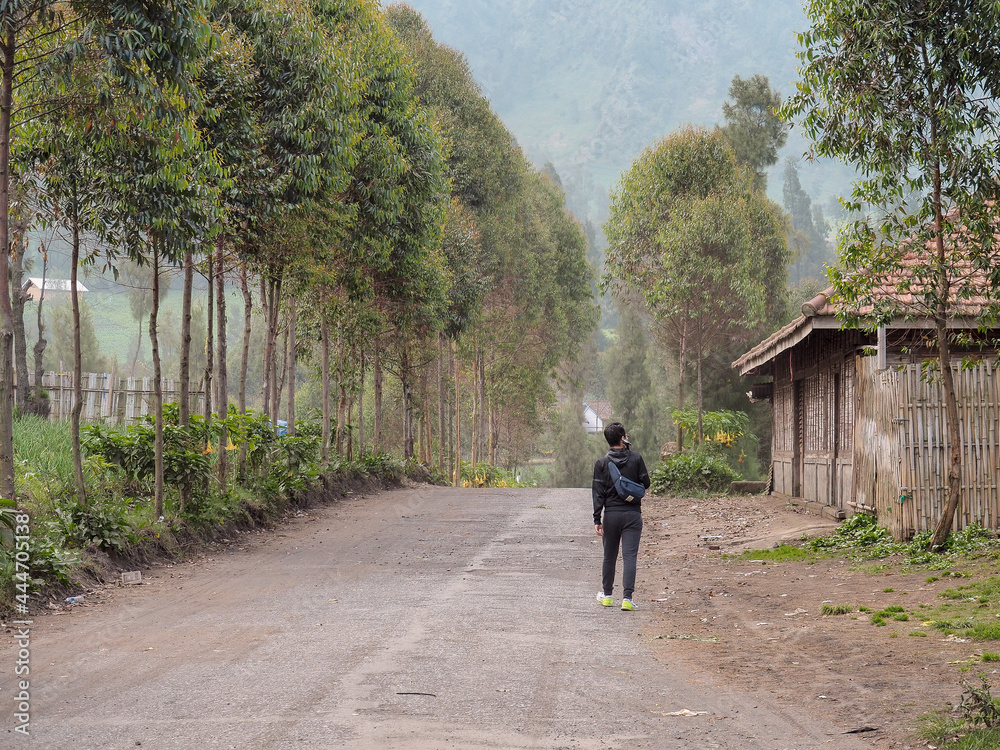 A man walking on a country road in Indonesia, ready for an adventure