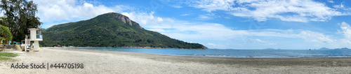 panorama wide natural photography beach photo with lifeguide station, tree, clouds and ocean water photo