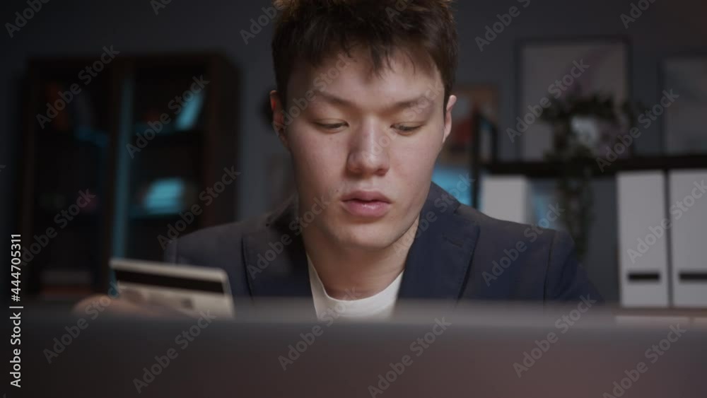 Portrait of young Asian man doing shopping online on laptop computer, using bank credit card, booking hotel. Korean student, Chinese guy, food delivery during coronavirus lockdown. Portrait of young Asian man doing shopping online on laptop computer, using bank credit card, booking hotel. Korean student, Chinese guy, food delivery during coronavirus lockdown.