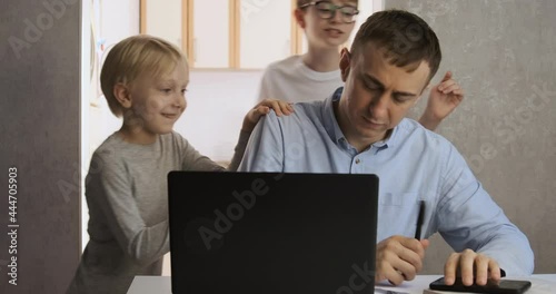 Children distract dad from work. Young male freelancer trying to work at home with two children.