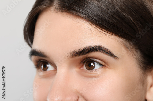 Woman after eyebrow tinting procedure on grey background, closeup