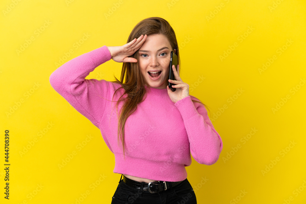 Teenager girl using mobile phone over isolated yellow background with surprise expression Teenager girl using mobile phone over isolated yellow background with surprise expression