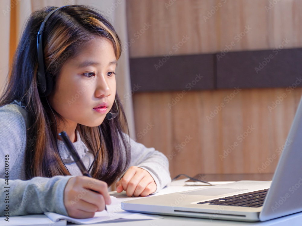 Asian girls study online with laptops. Kid wear headset typing keyboard notebook learning using internet lessons on quarantine. Students learn with internet online class from school Covid-19 Asian girls study online with laptops. Kid wear headset typing keyboard notebook learning using internet lessons on quarantine. Students learn with internet online class from school Covid-19