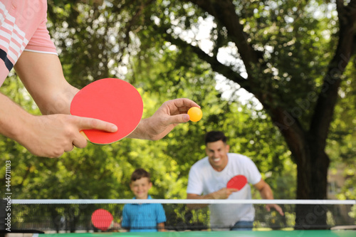 Family with child playing ping pong in park, closeup photo