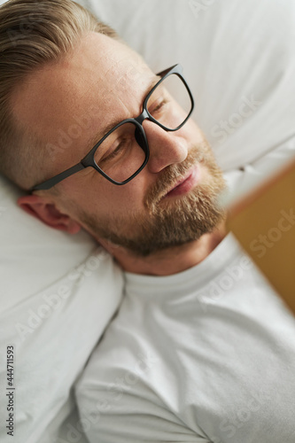 Happy man with book resting on bed