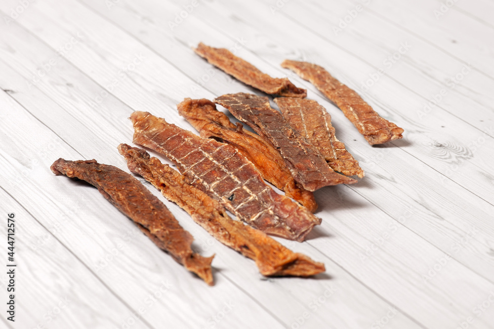Sliced beef udder cut for pieces, dehydrated and lying down on wooden white background. Homemade natural dry dog treats. Closeup, copy space. Sliced beef udder cut for pieces, dehydrated and lying down on wooden white background. Homemade natural dry dog treats. Closeup, copy space.