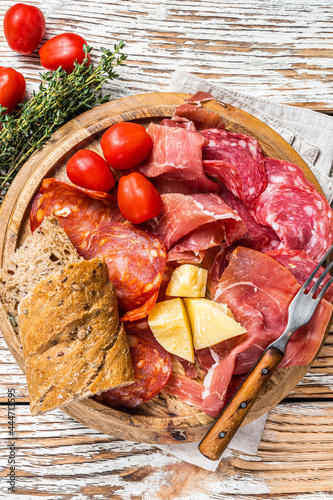 Cold meat plate, charcuterie traditional Spanish tapas on a wooden board. White wooden background. Top view