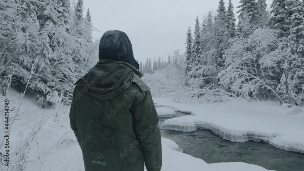 View of a man from the back on the river bank in the winter forest. Calm and contemplation concept View of a man from the back on the river bank in the winter forest. Calm and contemplation concept