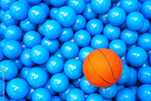 Children's orange rubber basketball Put it on a lot of blue rubber balls. The blue color is used as a beautiful background image.