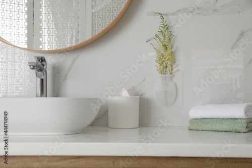 Silicone vase with flowers on white marble wall over countertop in stylish bathroom photo