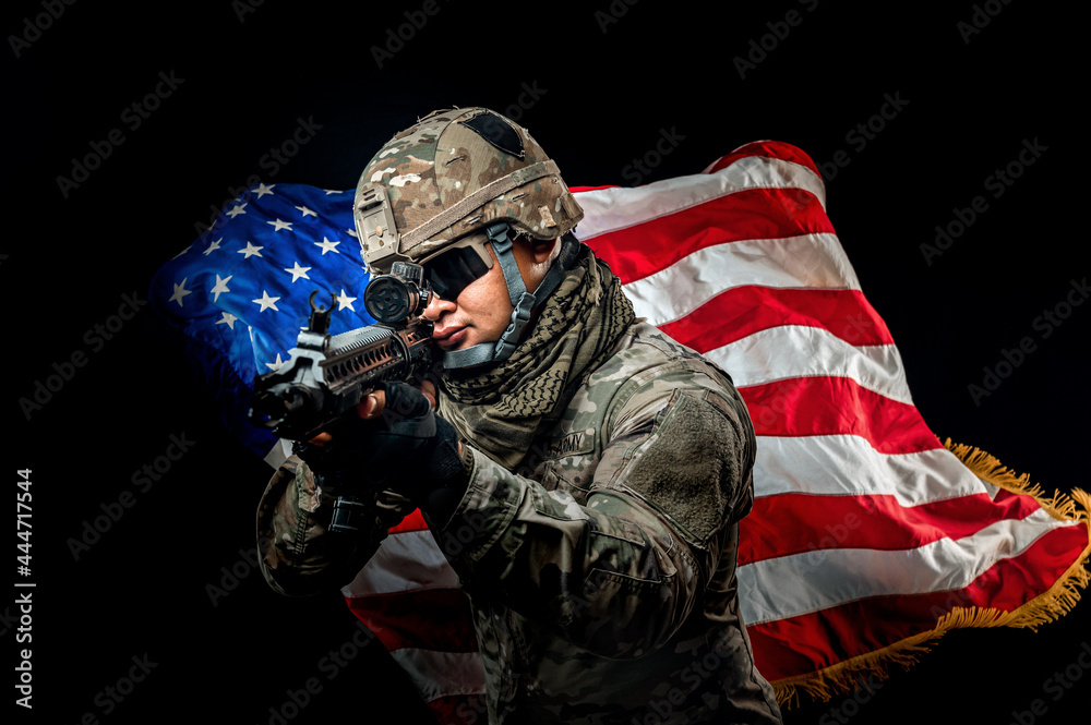 Photo of soldier holding the USA flag in background. Special force United States soldier or military contractors holding rifle. Image on background. soldier, army, war, weapon and technology concept. Photo of soldier holding the USA flag in background. Special force United States soldier or military contractors holding rifle. Image on background. soldier, army, war, weapon and technology concept.