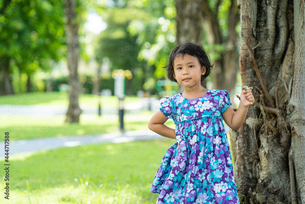 Adorable little girl standing against the tree in summer. Adorable little girl standing against the tree in summer.