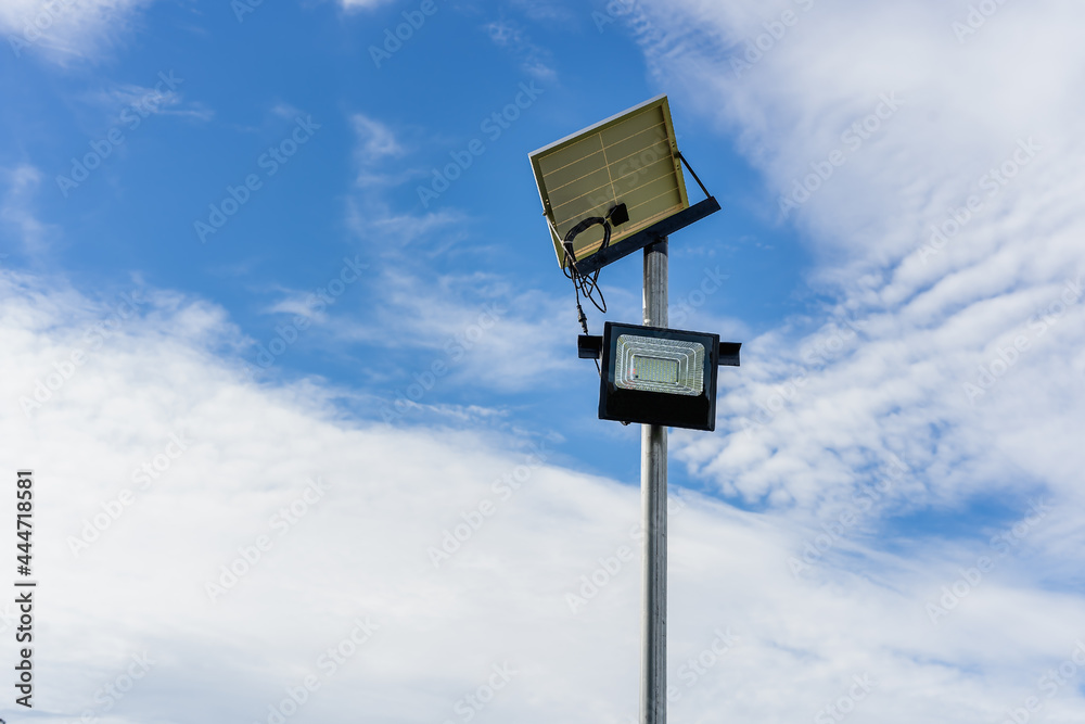 Small Solar Panel for light in street or park with white clouds and blue sky. Outdoor lighting pole with small size solar panel power by themself, new technology and energy trend for public area Small Solar Panel for light in street or park with white clouds and blue sky. Outdoor lighting pole with small size solar panel power by themself, new technology and energy trend for public area