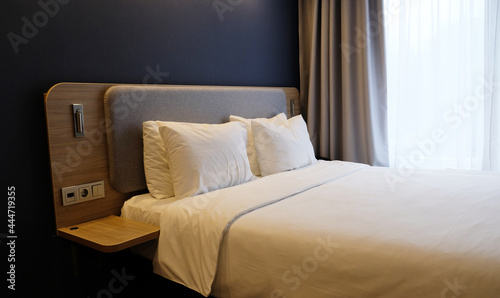 Close-up fragment of bedroom with empty bedside table  reading lamp and a USB socket in modern interior    design home or hotel. Soft pillow and blanket  stylish comfortable furniture.