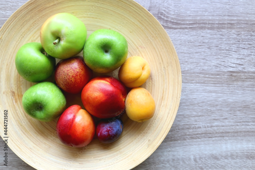 Wooden bowl with various colorful fruit on dark background. Top view. Wooden bowl with various colorful fruit on dark background. Top view.